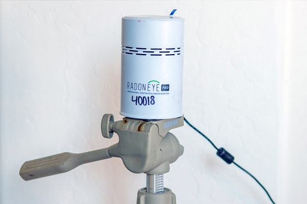 Radon testing device that is setup against a wall in a home.