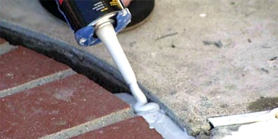 Cracks in the foundation of a home in phoenix being caulked with specialized sealant to prevent gas from coming up through the ground.